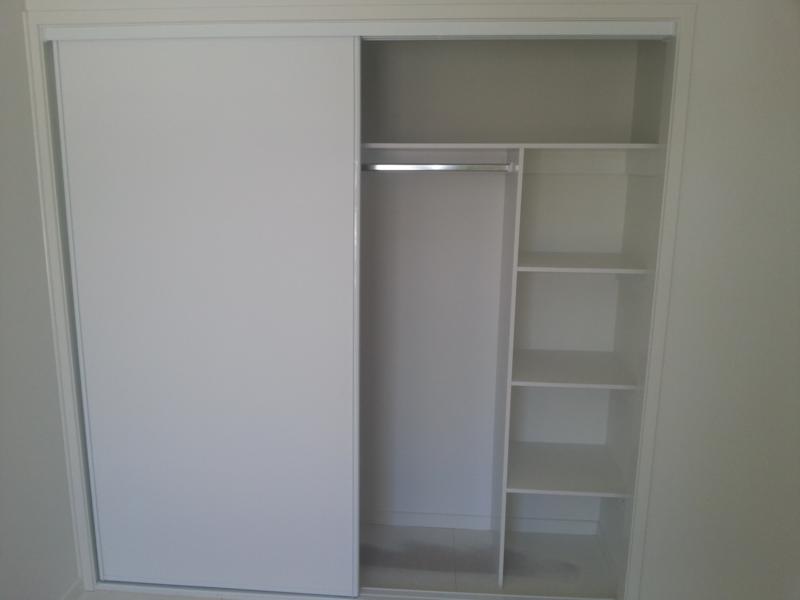 Framed Vinly Wardrobe Door in white in front of wardrobe shelving
