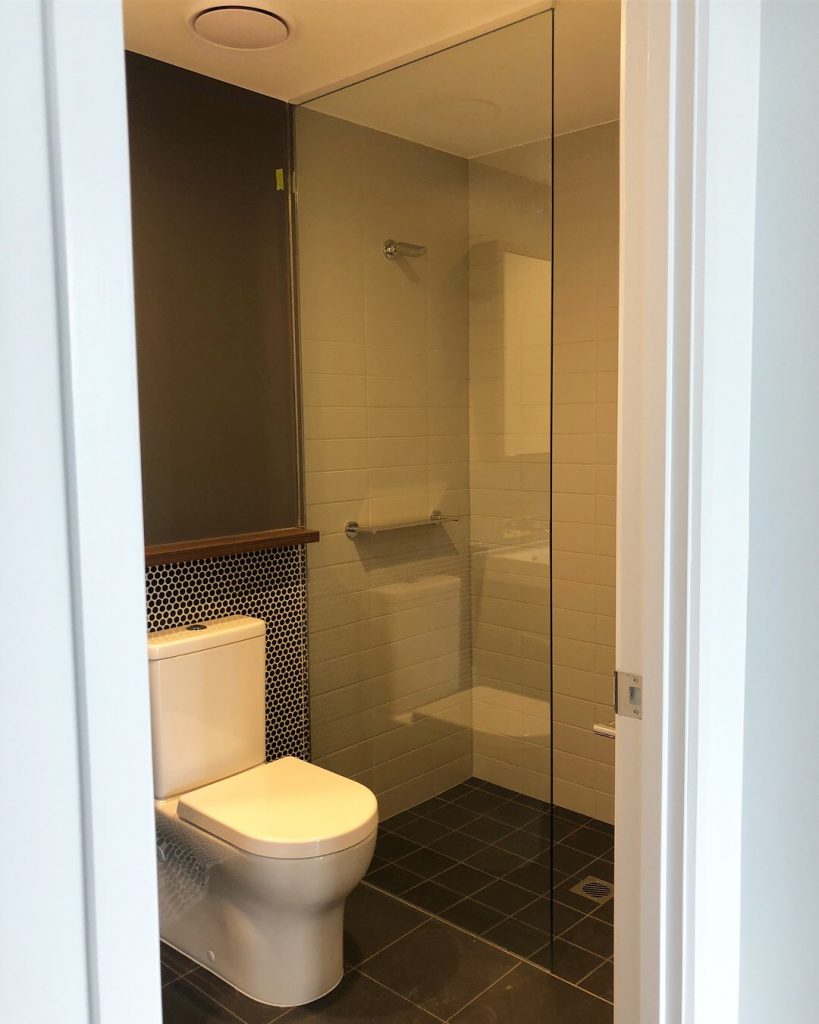Frameless Panel in bathroom with backsplash and toilet