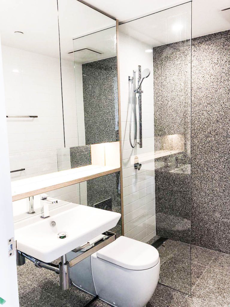 Frameless Panel in beautiful backsplash/tiled bathroom with shower overhead