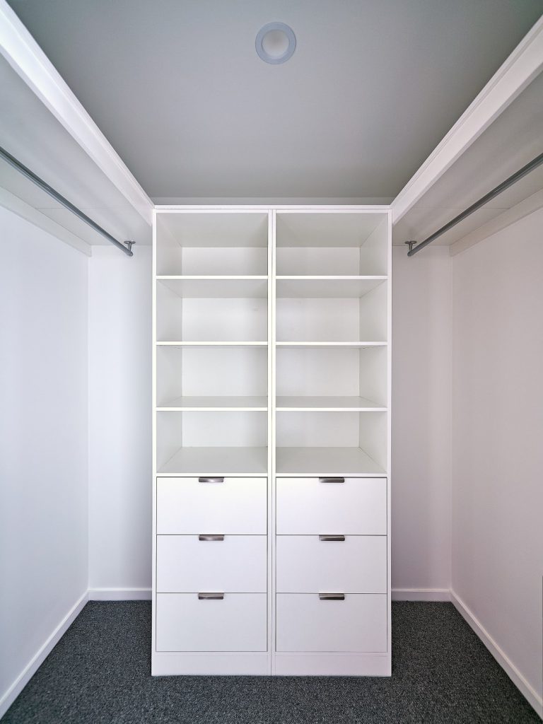 Walk-in-Wardrobe - Standard White Board Shelving with Finger Pull Handles on the Banks of Drawers & Round Chrome Hanging Rods