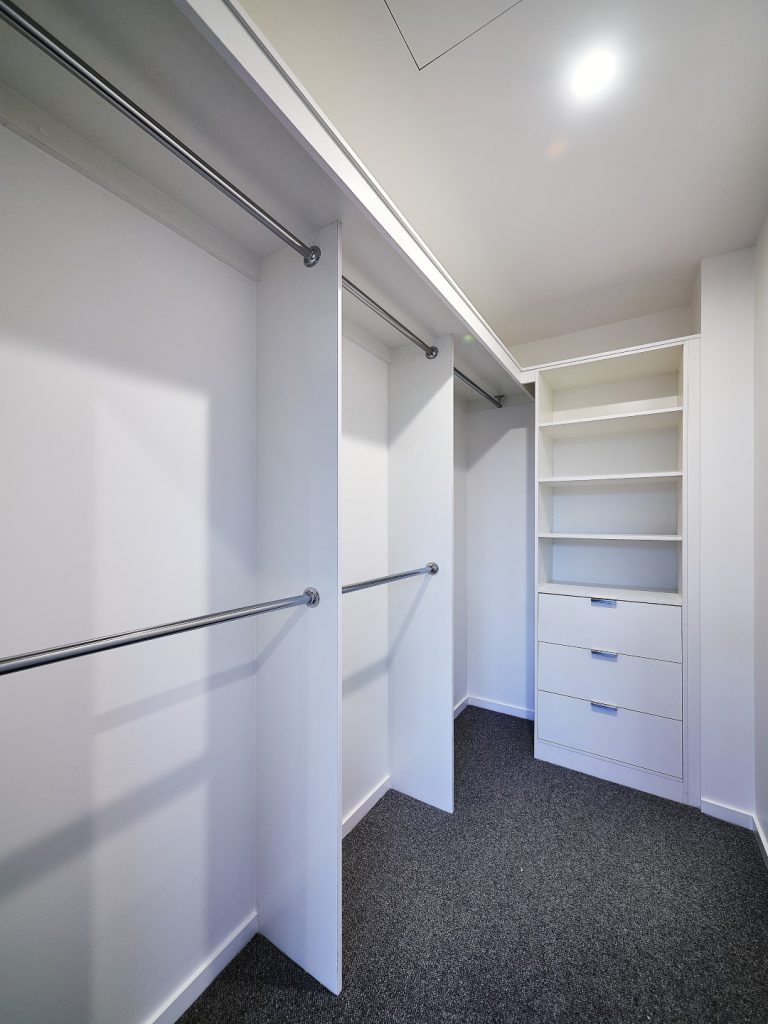 Built-in Wardrobe - Standard White Board Shelving with Finger Pull Handles on the Bank of Drawers & Round Chrome Hanging Rods