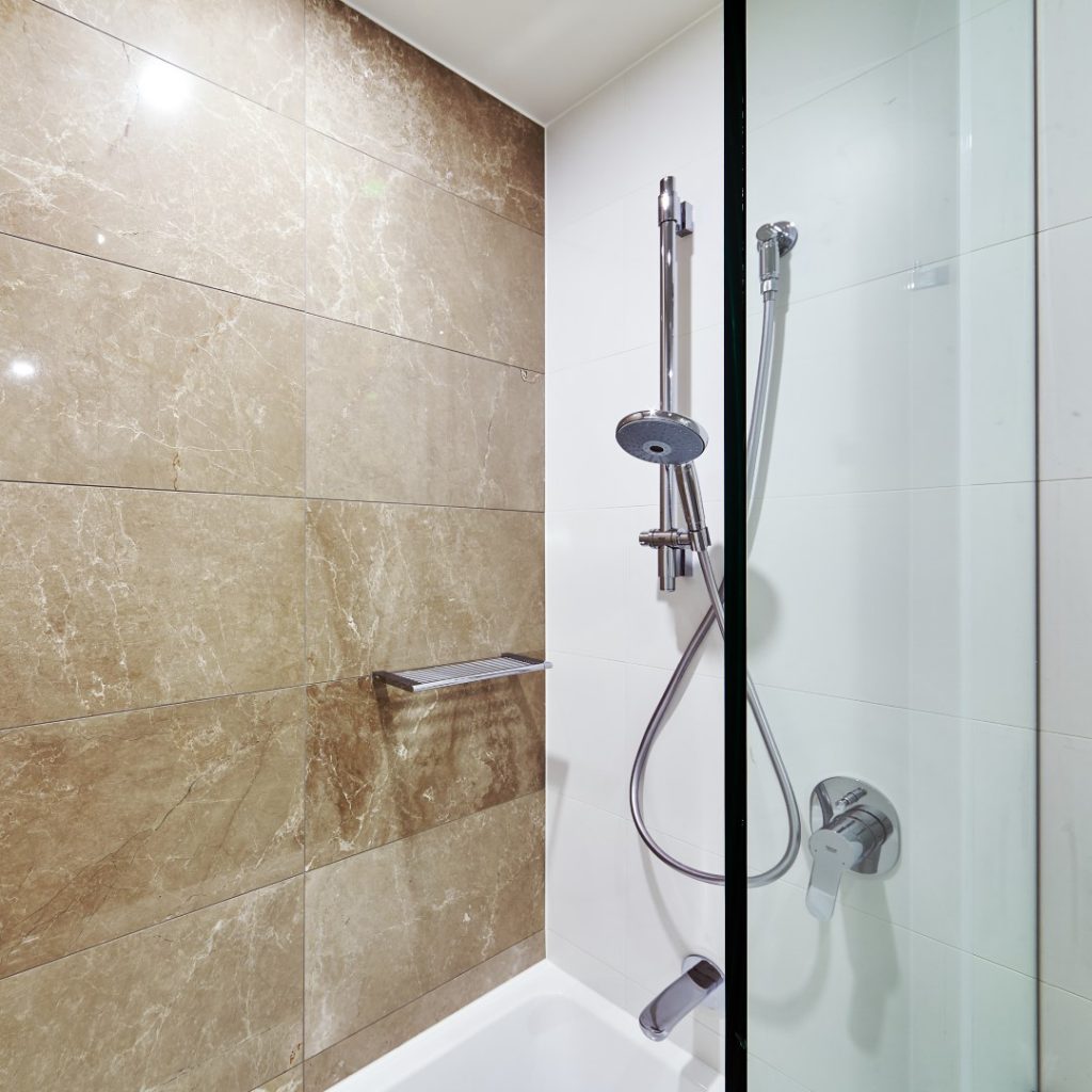 Frameless Shower Screen Panel in small bathroom with tub and shower overhead with Brown Tiles