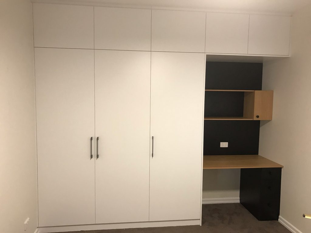 White Board Wardrobe with Hinged Doors and Polished Silver Handles; Extra Storage Cupboards above Wardrobe with a Colour Board Desk on Right Hand Side
