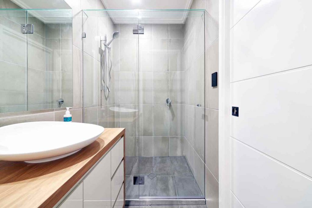 Simple Frameless hinged shower screen on neat gray bathroom