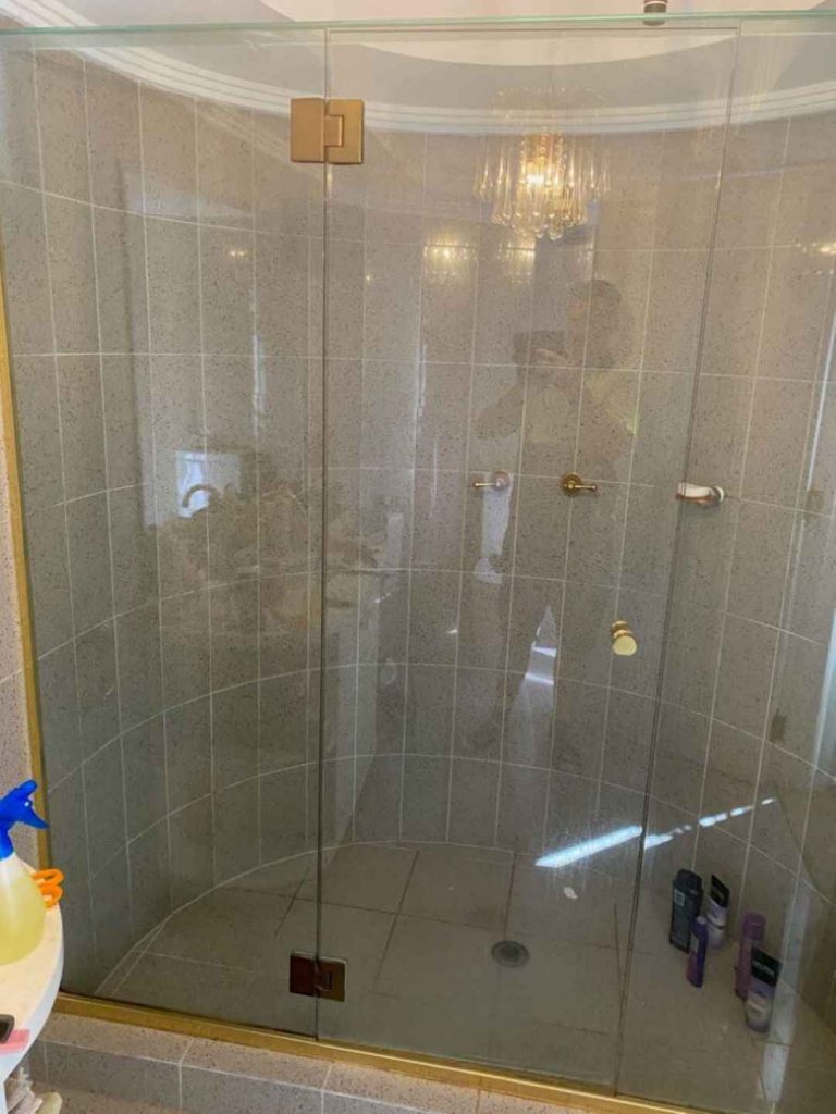 Frameless hinged shower screen on top of Gold bathroom brackets