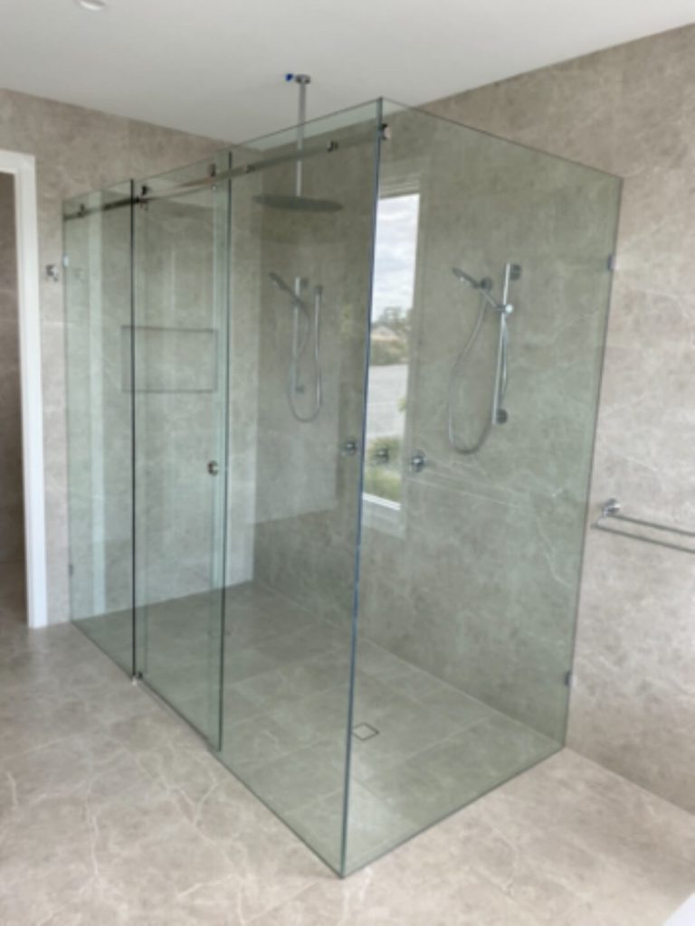 Frameless Sliding Shower Screen in a marbled tile bathroom with 2 showerheads and rain shower head