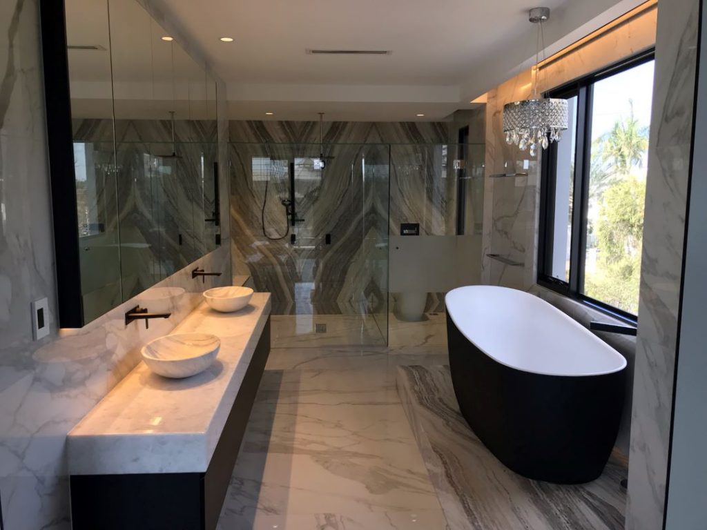 Frameless Hinged Shower Screen on a modern ensuite with vanity, bathtub and chandelier