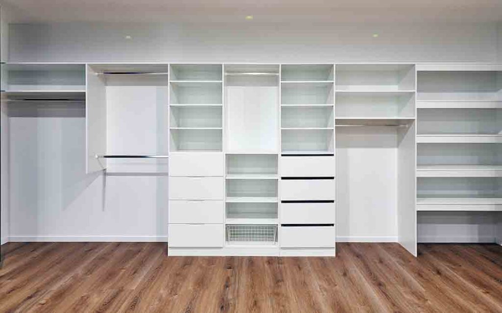 built-in wardrobe white shelving with finger pull drawers and chrome hanging rails for garment