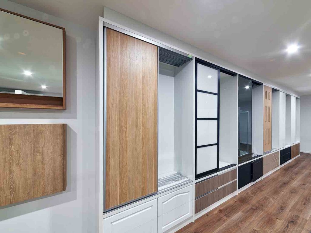 rows of wardrobes with different styles of robe doors in a showroom